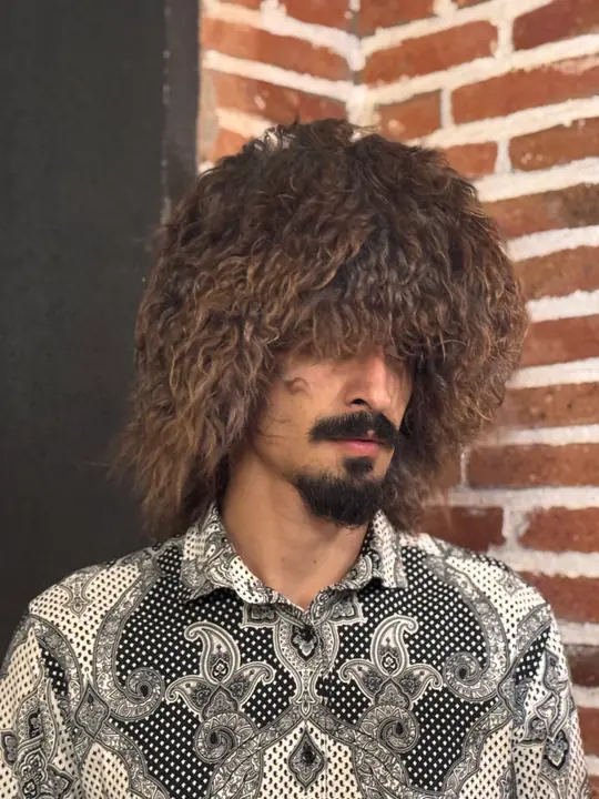 Goat fur papakha with long curly light brown fur, worn by a man, three-quarter view