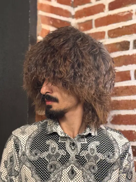 Goat fur papakha with long curly light brown fur, worn by a man, side view