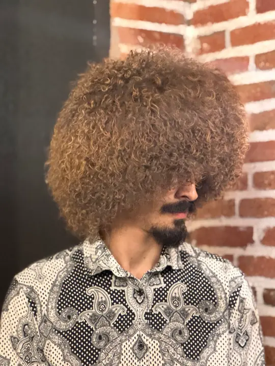 Goat fur papakha with dense curly brown fur, worn by a man, side view