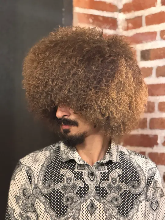 Goat fur papakha with dense curly brown fur, worn by a man, three-quarter view