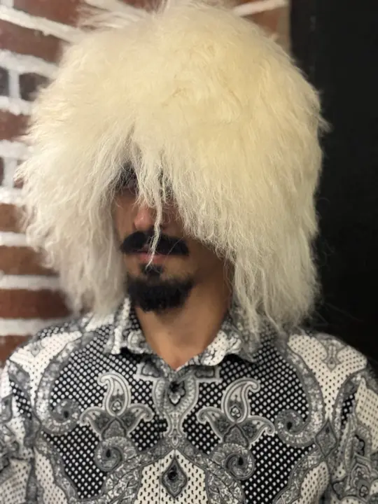 White sheepskin papakha with long straight wool, worn by a man, front view