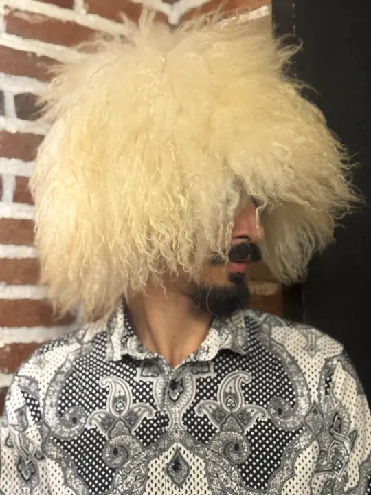 White sheepskin papakha with long wavy wool, worn by a man, head turned to the side