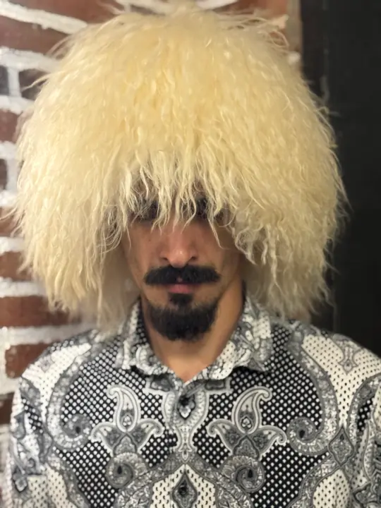 White sheepskin papakha with long wavy wool, worn by a man, front view
